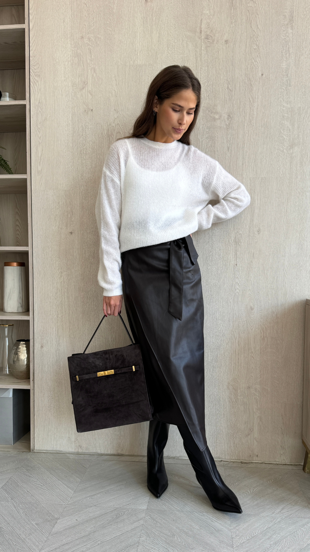 white knit sweater paired with a black faux leather wrap midi skirt, styled with pointed-toe black heeled boots