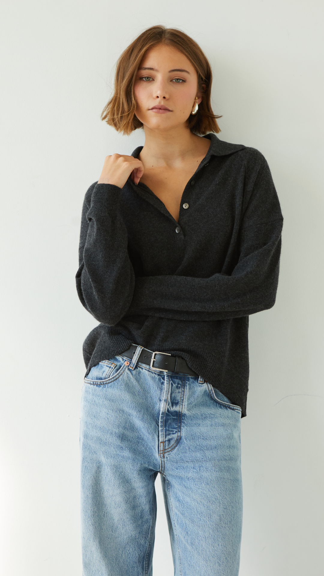 dark grey collared sweater with button details, paired with light blue jeans and a black belt