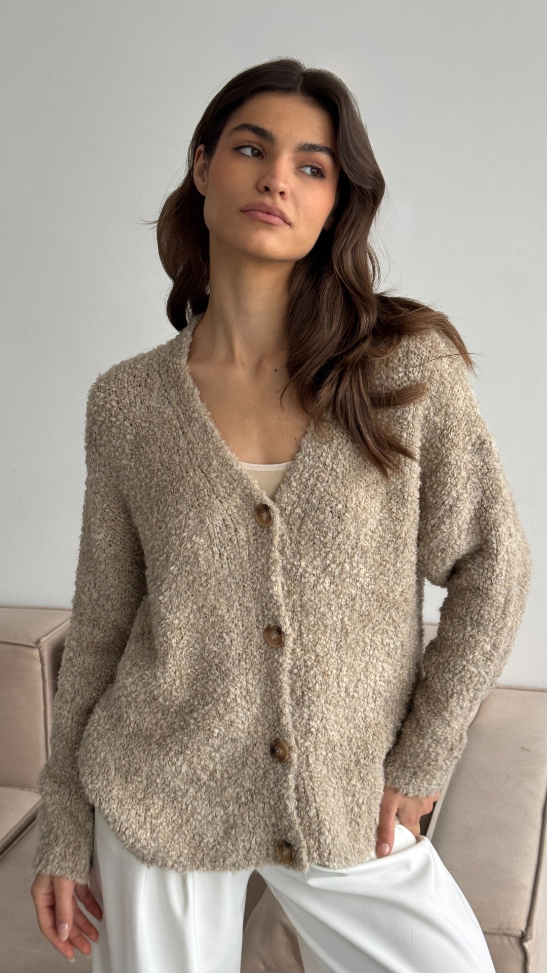beige textured cardigan with a button-front design, paired with white trousers