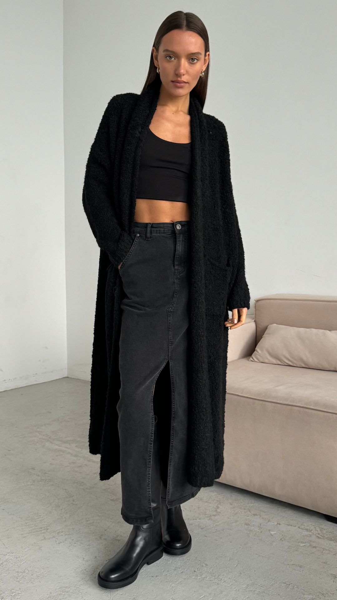 black oversized fluffy cardigan over a black crop top, paired with a black denim skirt featuring a slit