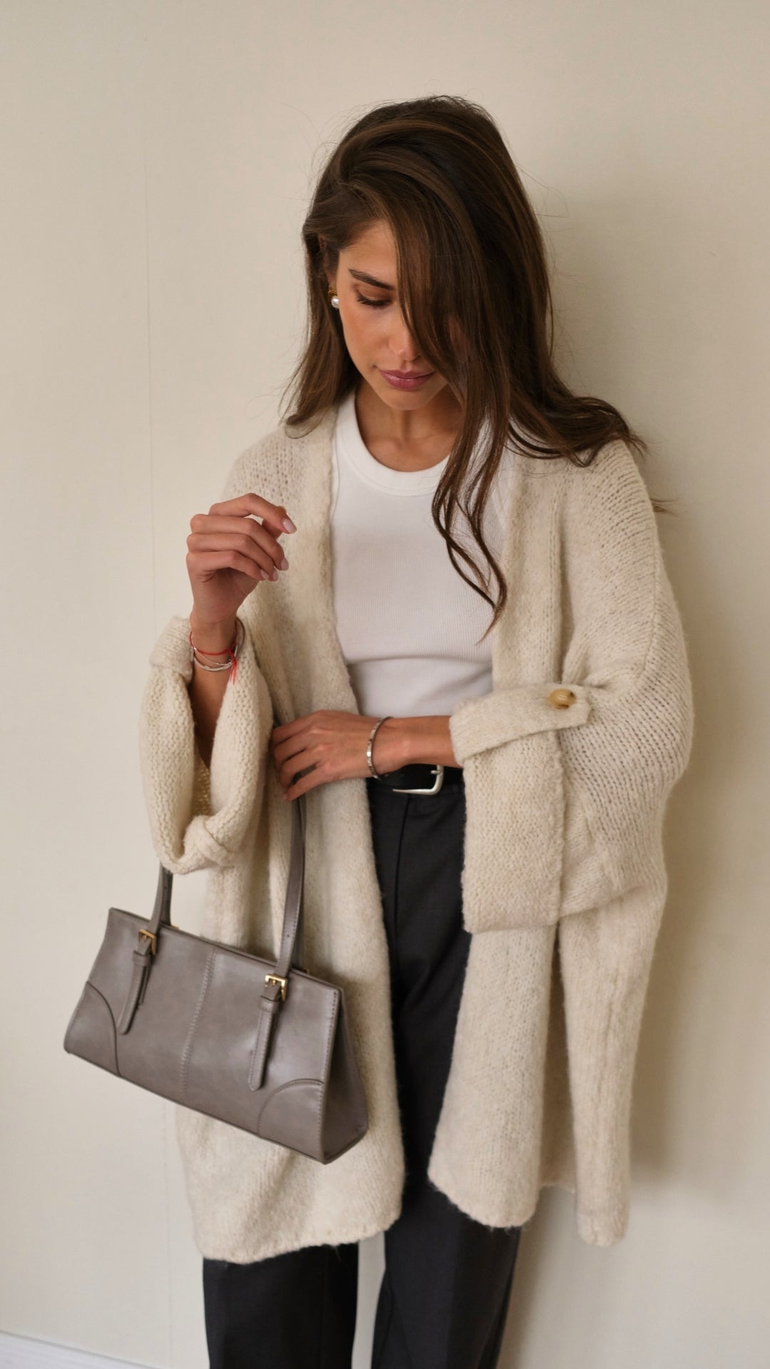 cream oversized cardigan over a white top, paired with black trousers and holding a taupe handbag