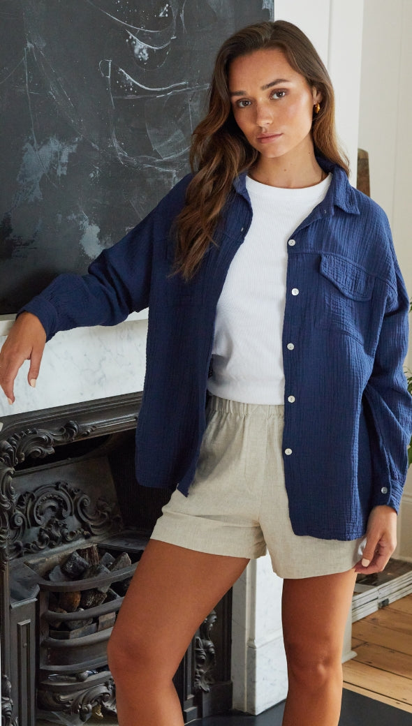 navy blue textured button-up shirt over a white top, paired with beige shorts
