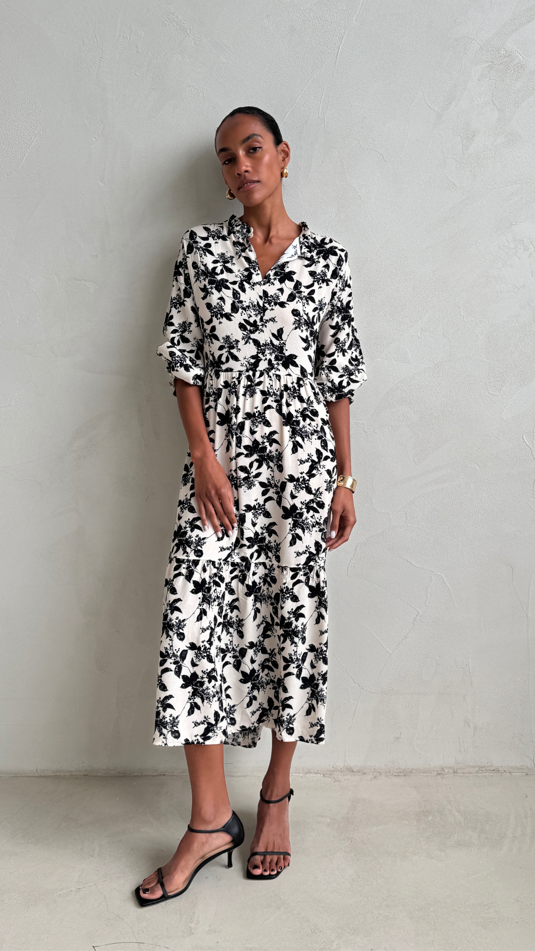 black and white floral-print midi dress with a collared neckline, three-quarter sleeves, and a cinched waist, styled with black strappy heeled sandals and gold accessories
