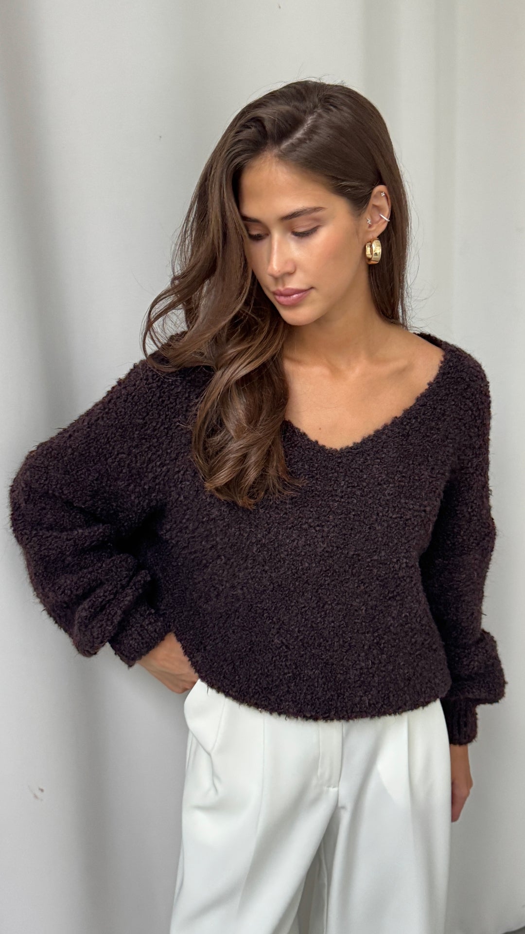 dark brown textured cropped sweater with a V-neckline, styled with high-waisted white trousers