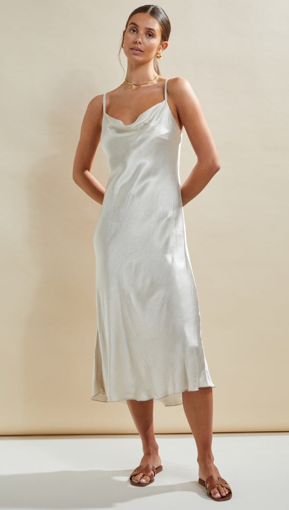 ivory satin slip dress featuring a draped cowl neckline and thin straps, styled with minimal gold jewellery and brown flat sandals