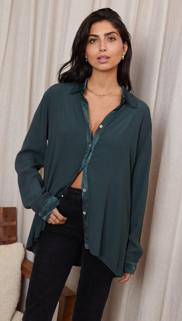 dark green button-up shirt with satin detailing, styled with black trousers