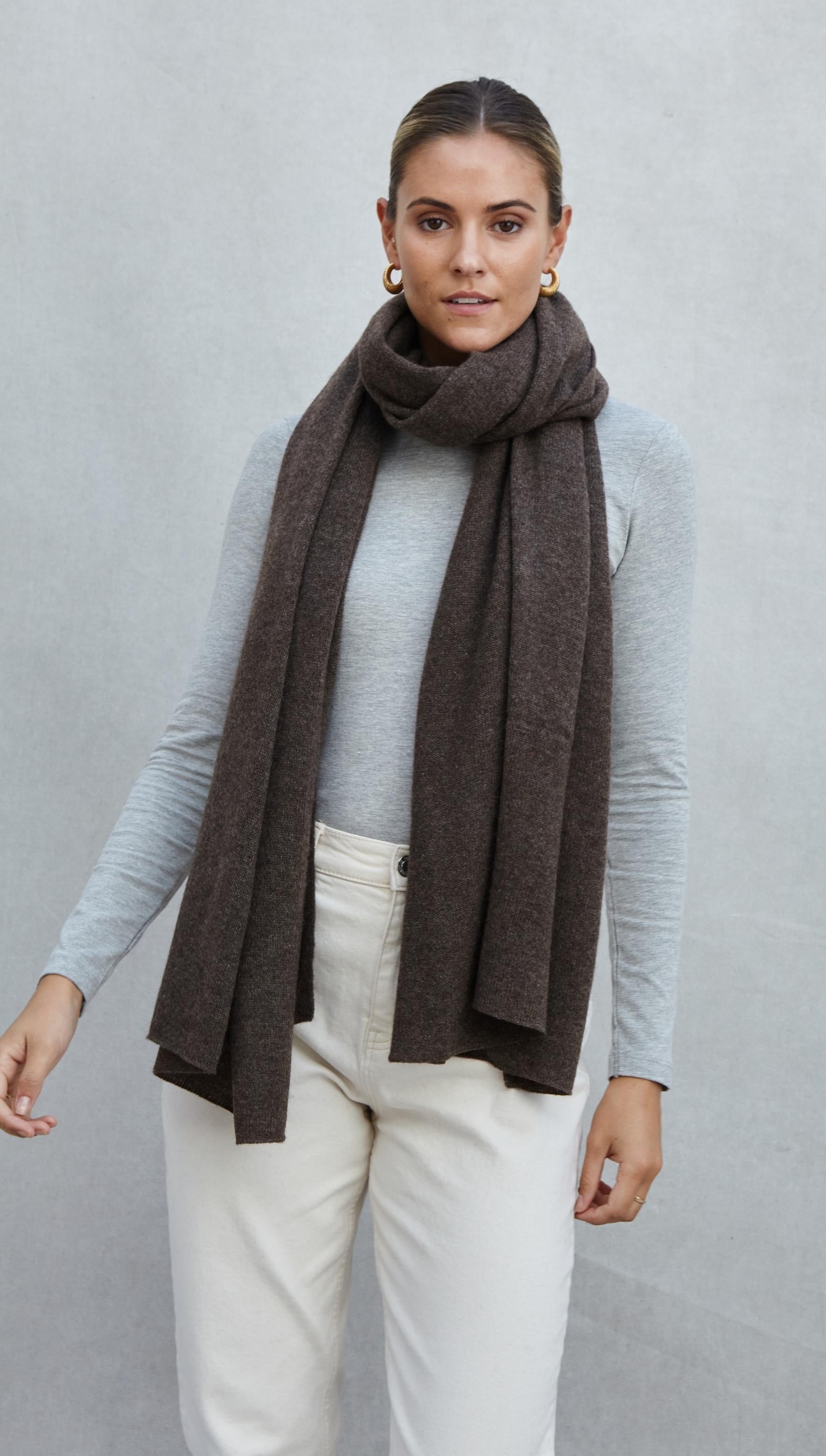 grey long-sleeve top paired with a dark brown scarf and cream trousers