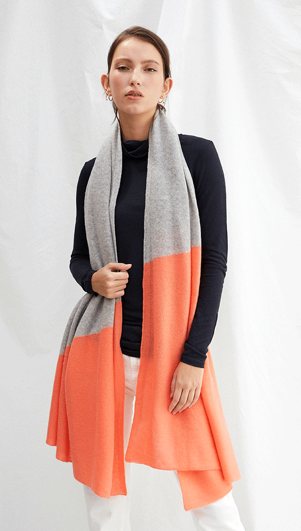 navy long-sleeve top paired with a grey and orange colour-blocked scarf, and white trousers