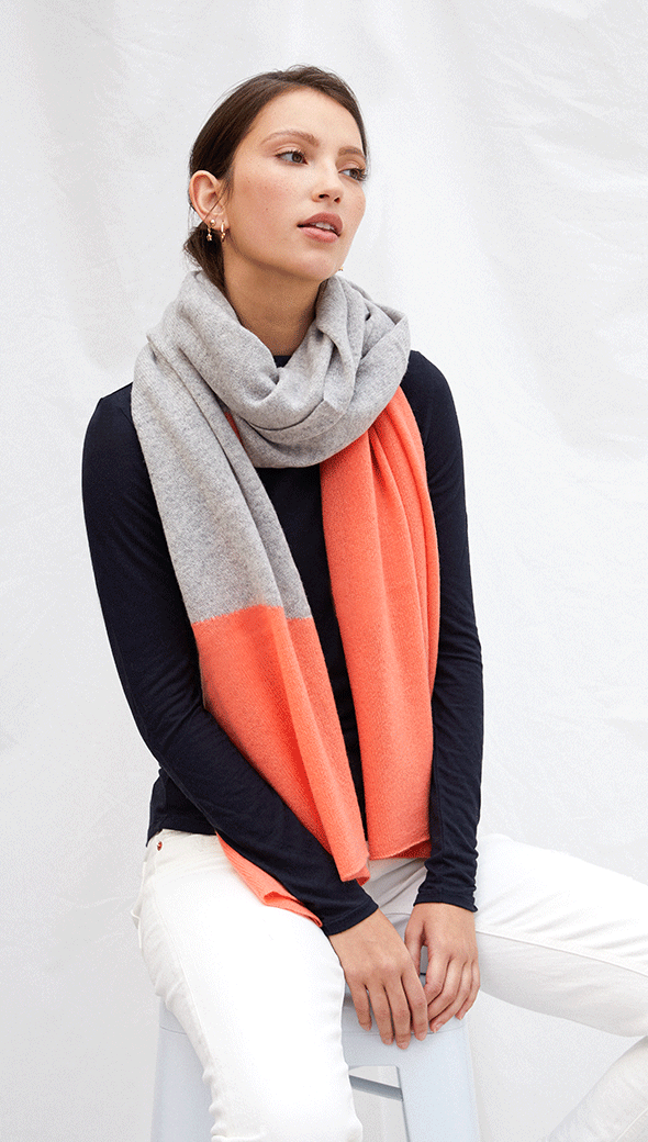 navy long-sleeve top paired with a grey and orange colour-blocked scarf, and white trousers