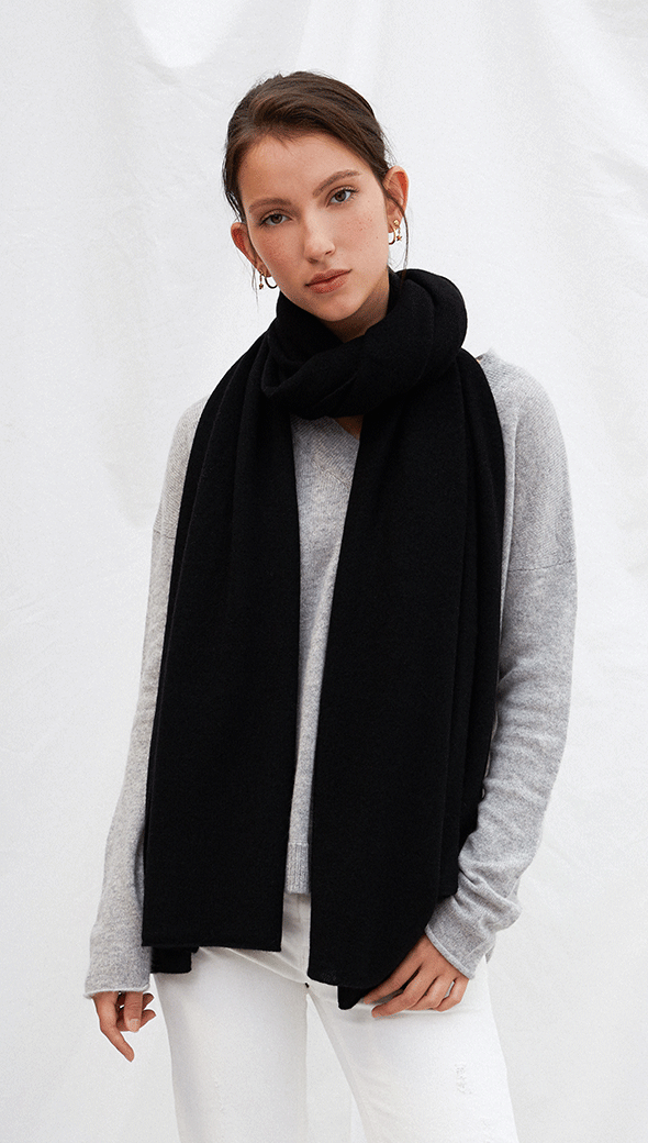 grey sweater with a large black scarf, paired with white trousers
