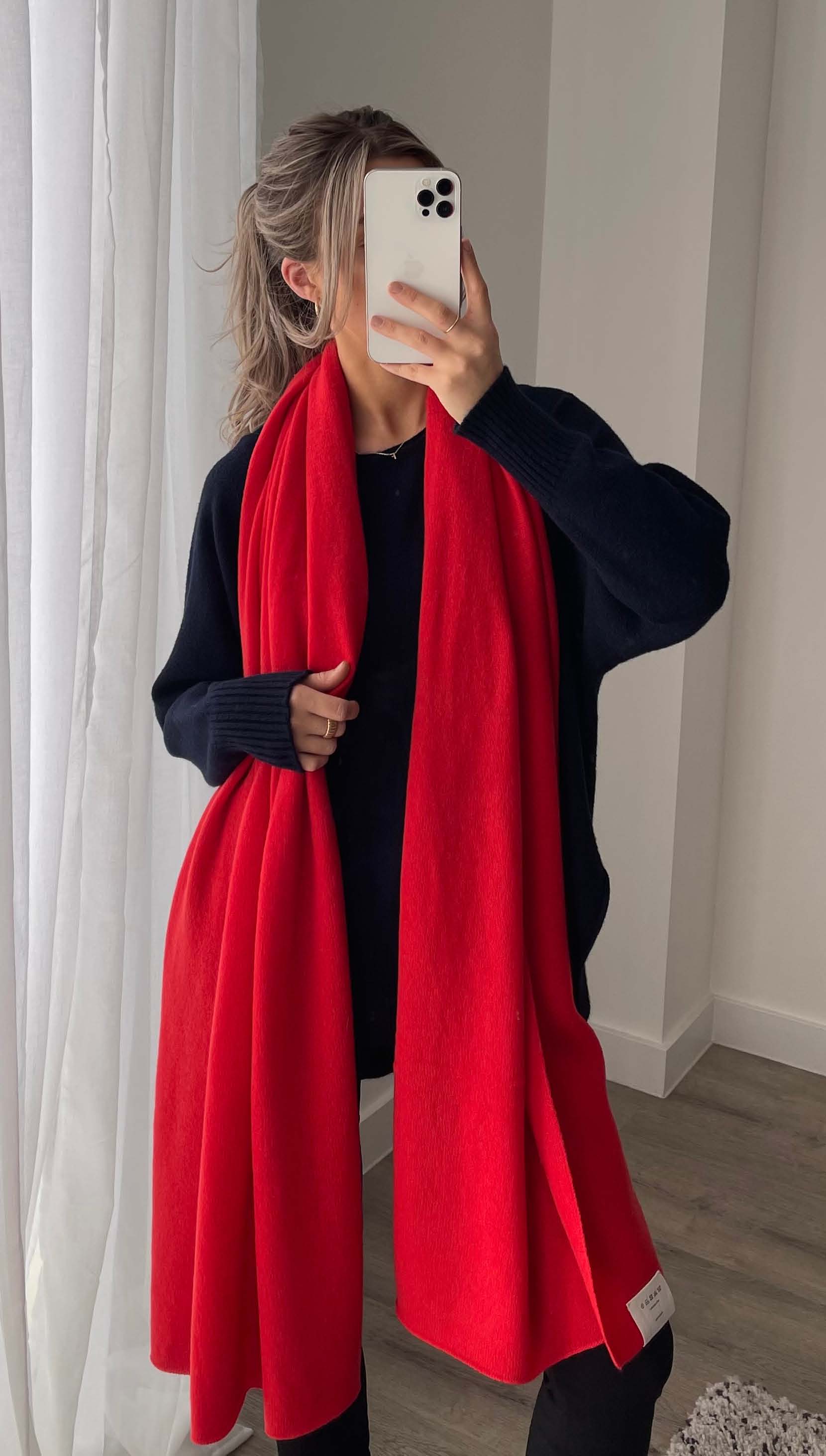 black sweater paired with a bright red scarf, styled with black trousers