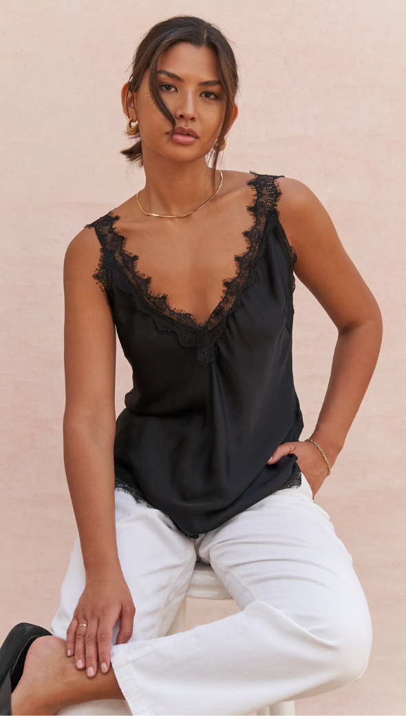 black lace-trimmed camisole with a V-neckline, paired with white trousers
