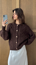 dark brown cable-knit cardigan with wooden buttons, paired with a white satin skirt