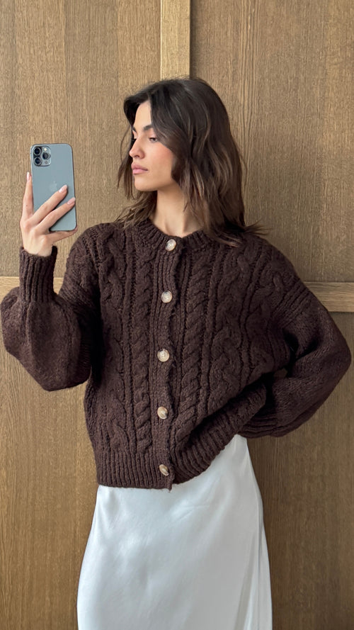 dark brown cable-knit cardigan with wooden buttons, paired with a white satin skirt