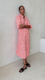 coral and white printed midi dress with a collared neckline and three-quarter sleeves, styled with black slide sandals