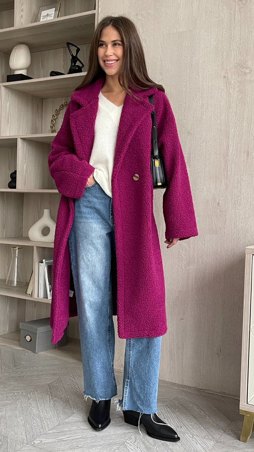 magenta oversized teddy coat layered over a white knit sweater, paired with light-wash straight-leg jeans and black ankle boots, accessorised with a sleek black shoulder bag