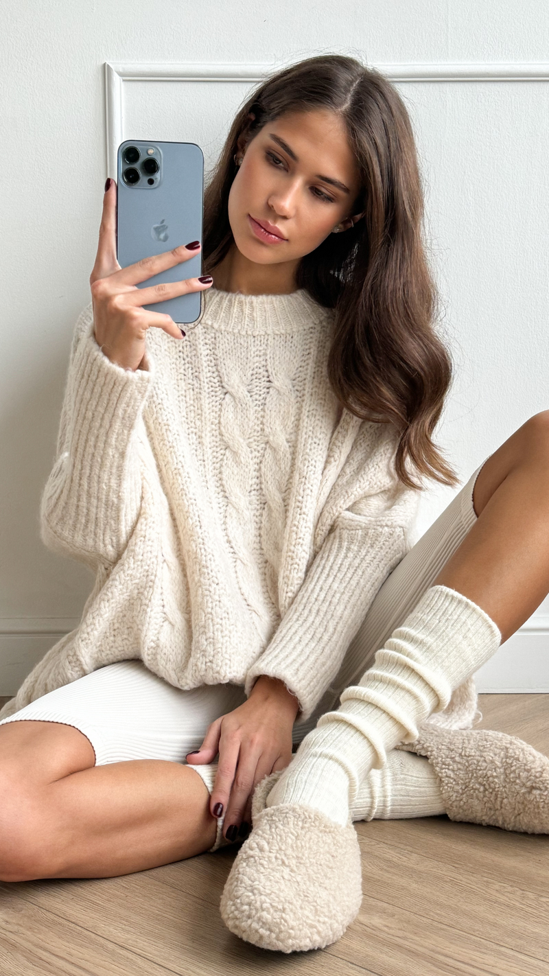 cream cable-knit sweater, matching knit socks, and cozy beige slippers