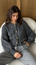 charcoal grey cable-knit cardigan with button details, paired with light grey tailored trousers