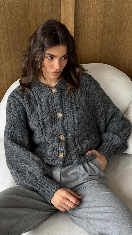 charcoal grey cable-knit cardigan with button details, paired with light grey tailored trousers