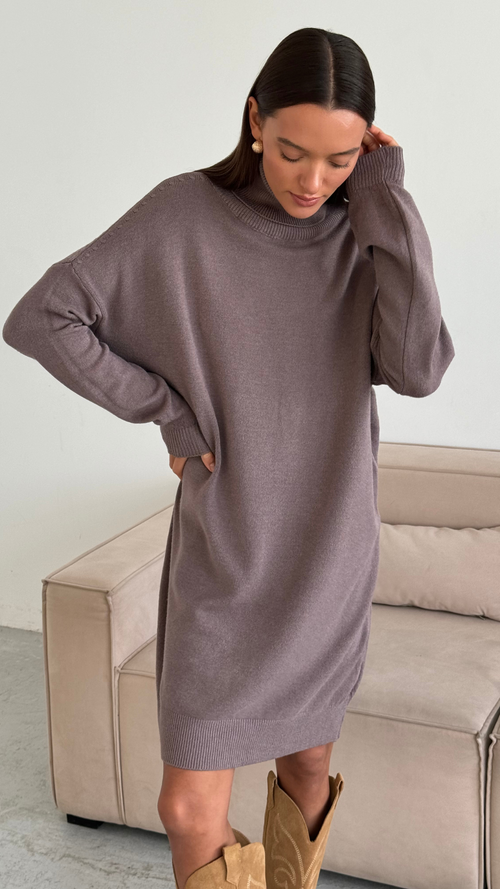 taupe oversized knit sweater dress with a high neckline and ribbed cuffs, styled with tan cowboy boots and gold hoop earrings