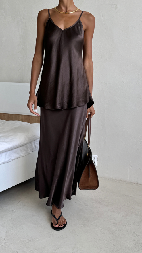 chocolate brown satin camisole with a matching satin maxi skirt, accessorised with a gold necklace, black sandals, and a brown leather handbag