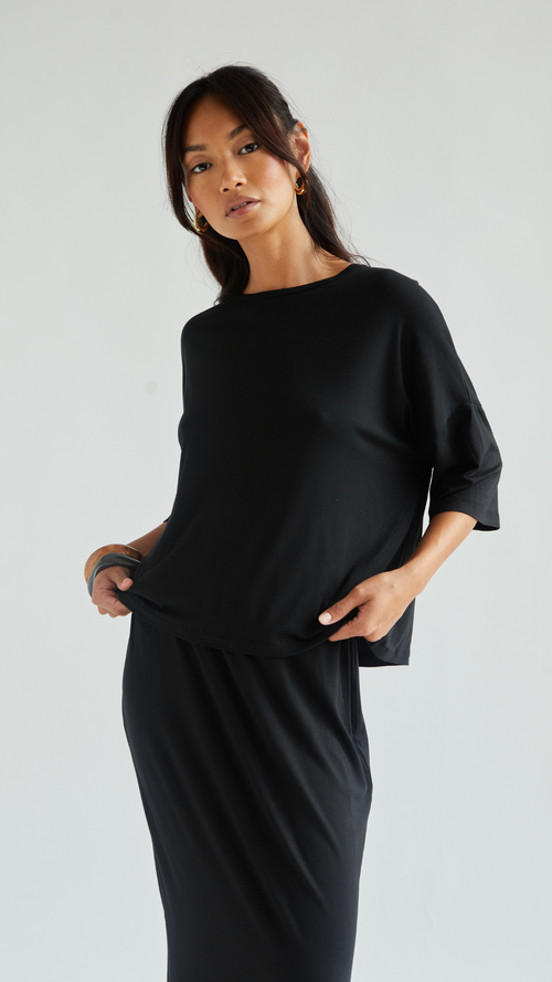 loose-fitting black top paired with a matching black skirt