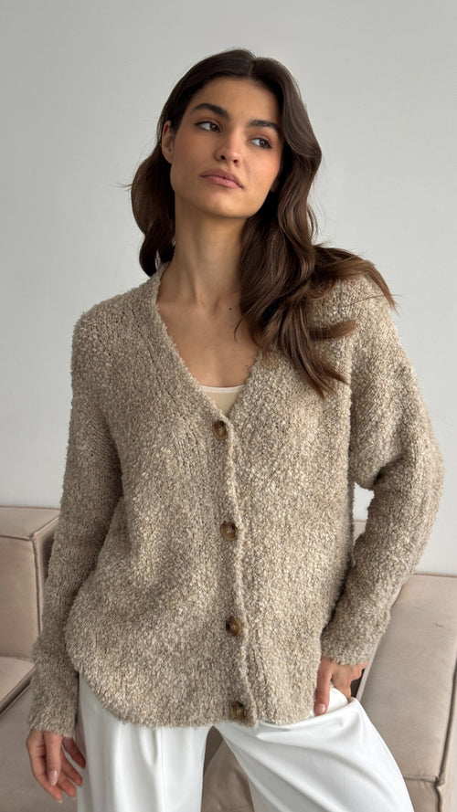 beige textured cardigan with a button-front design, paired with white trousers