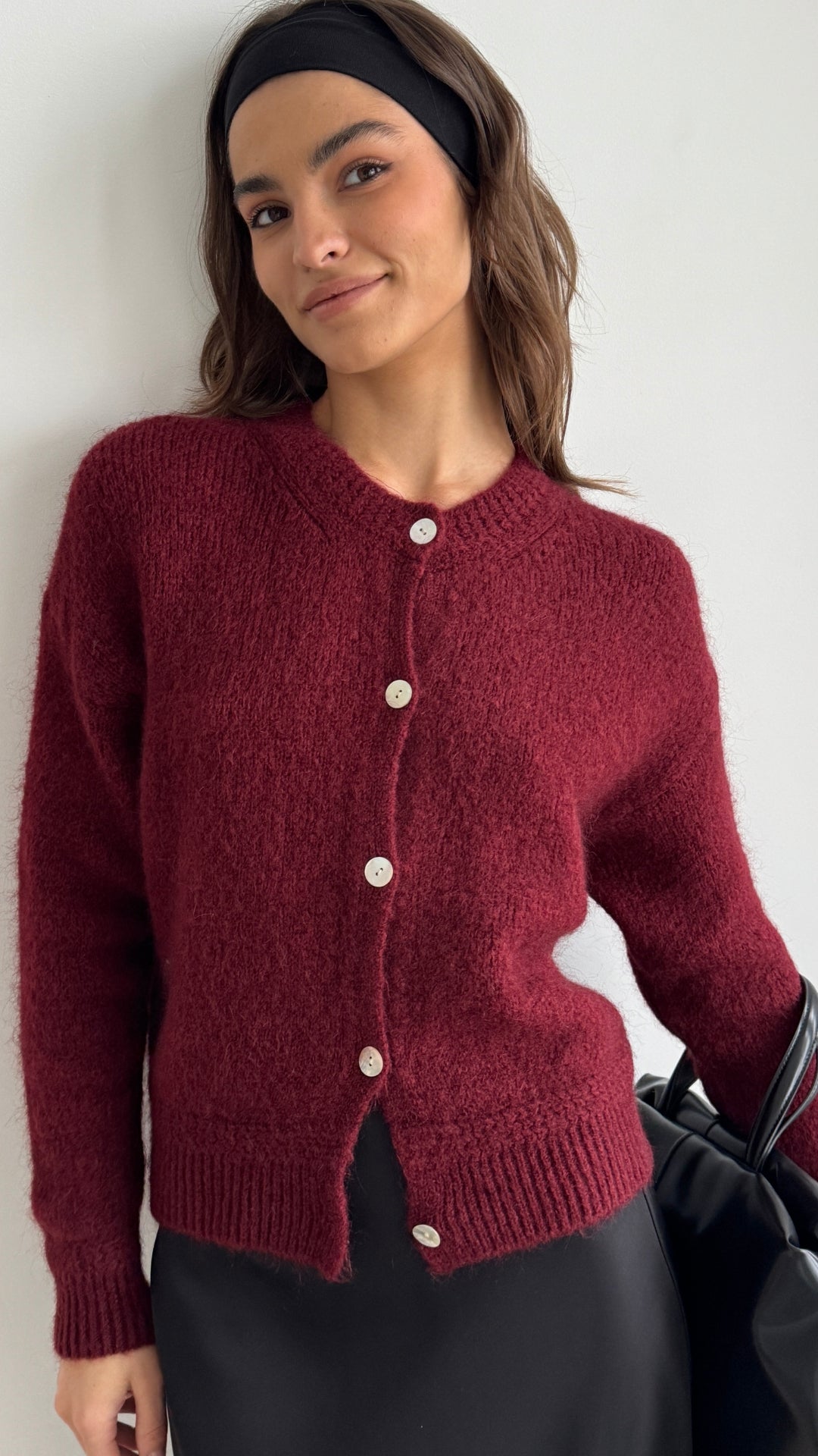 deep red fuzzy cardigan with button details, styled with a black satin skirt and a matching black headband