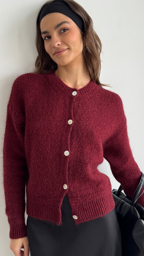 deep red fuzzy cardigan with button details, styled with a black satin skirt and a matching black headband