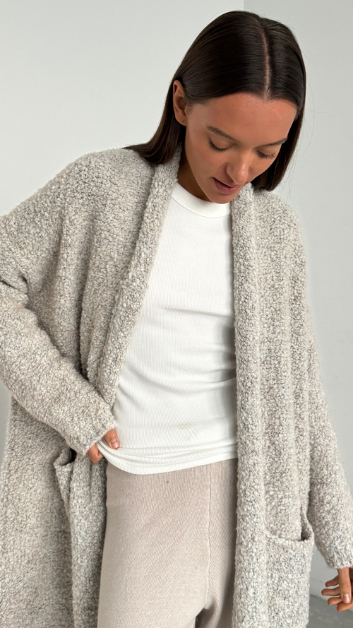 soft grey fluffy cardigan over a white ribbed long-sleeve top and light beige trousers