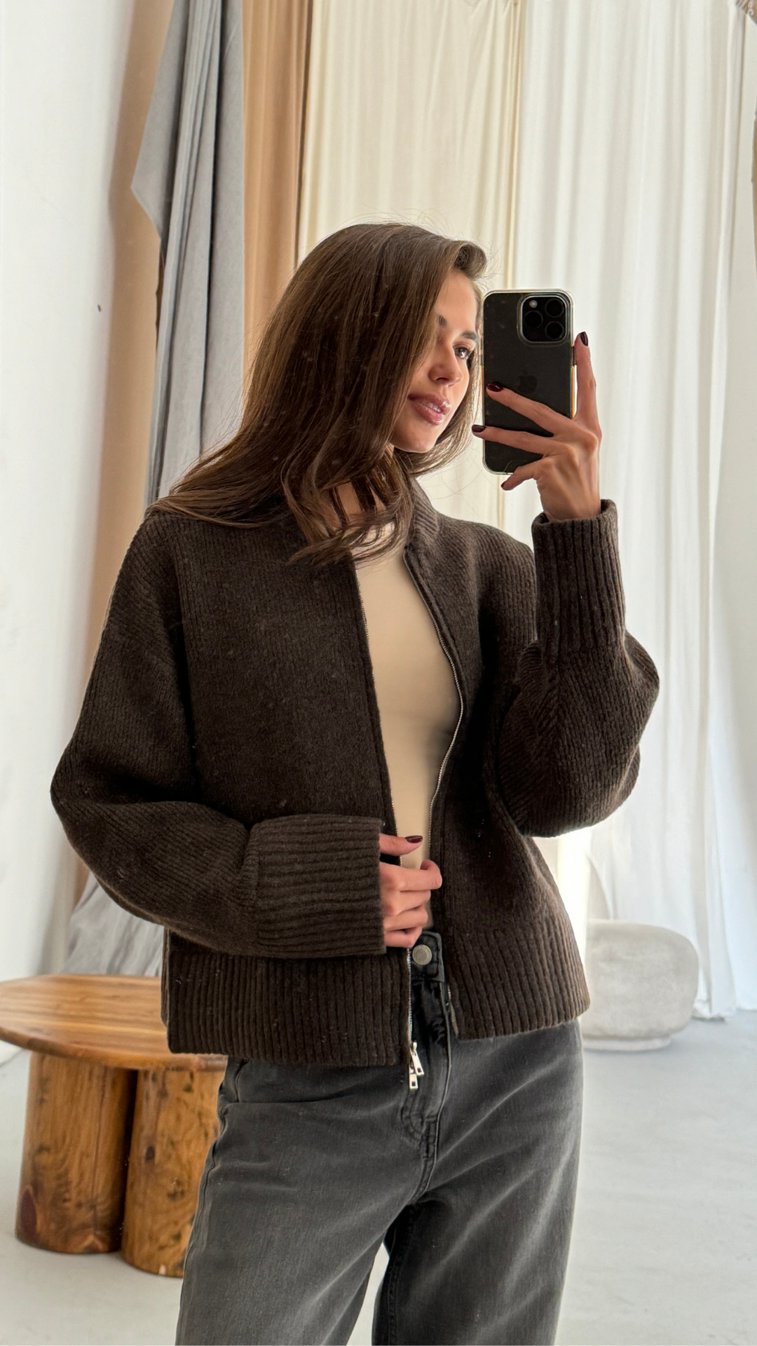 dark brown cropped zip-up cardigan over a beige top, paired with high-waisted black jeans