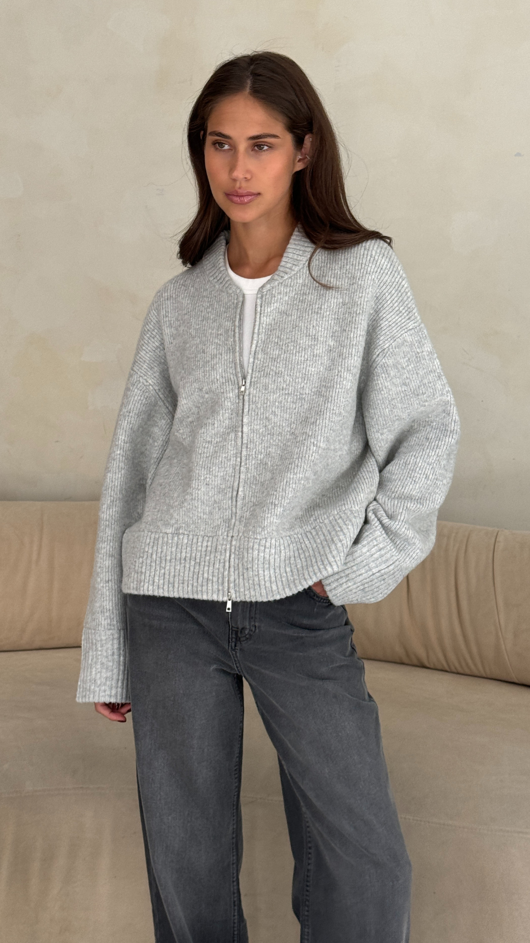 light grey zip-up knitted sweater over a white t-shirt, paired with dark grey jeans