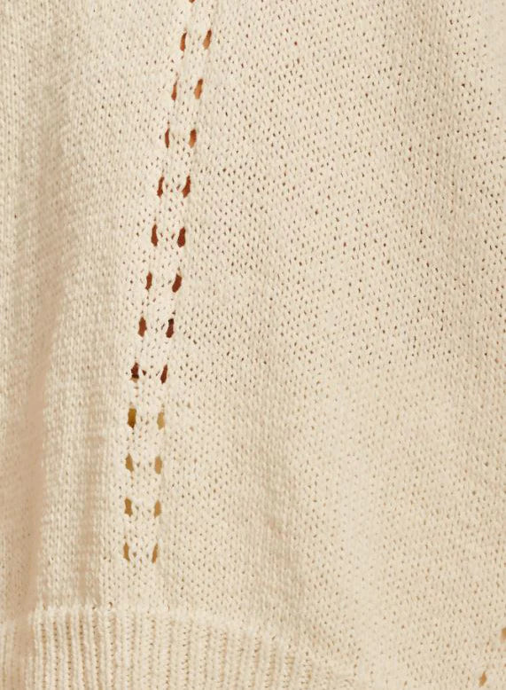 cream knit fabric featuring a textured pattern with delicate openwork detailing and a ribbed hem