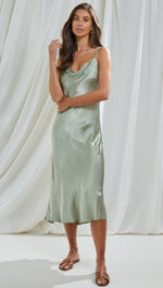 sage green satin slip dress featuring a draped cowl neckline and midi-length hem, styled with brown flat sandals and minimal gold jewellery