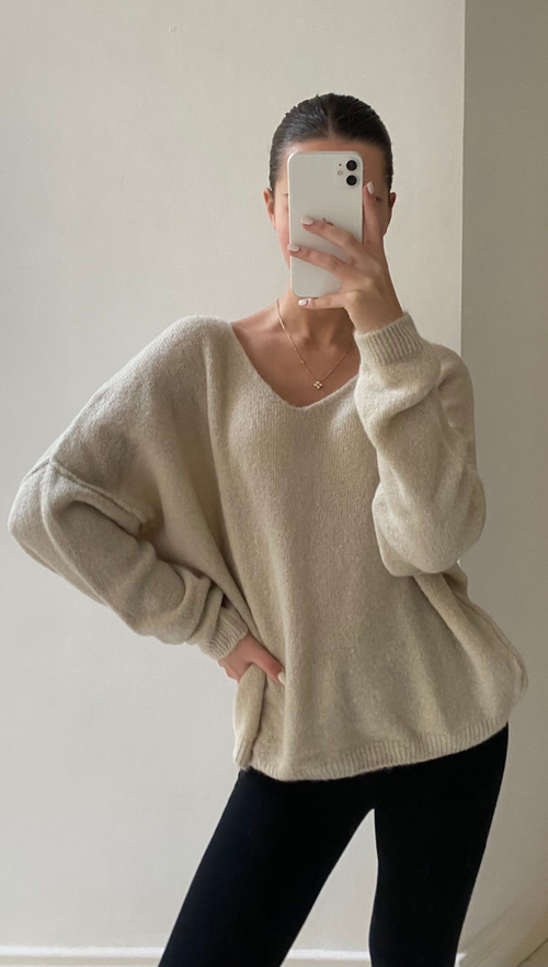beige oversized V-neck sweater with black fitted trousers