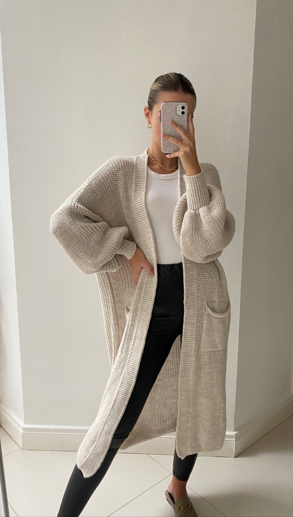 beige knitted cardigan over a white top, paired with black leather leggings