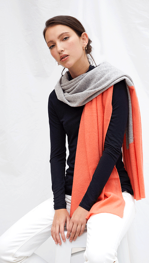 navy long-sleeve top paired with a grey and orange colour-blocked scarf, and white trousers