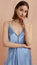 light blue satin camisole featuring a deep V-neckline, button-down detail, and thin spaghetti straps, styled with gold jewellery