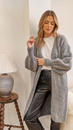 grey oversized knitted cardigan over a white t-shirt and black leather trousers